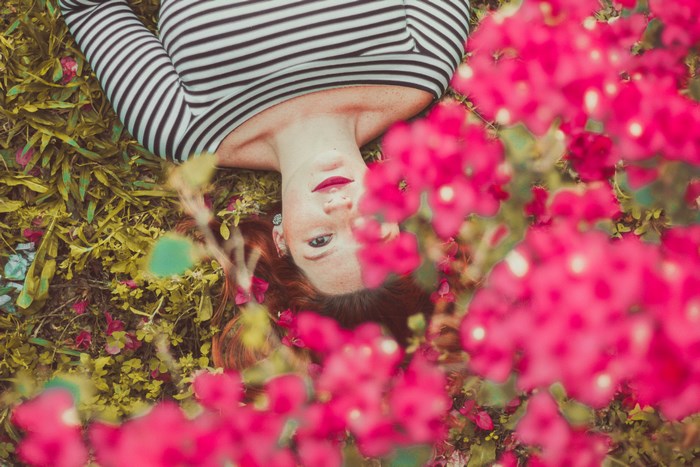 Woman lying on grass with pink flowers