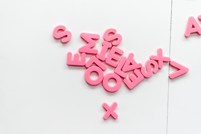 Pink alphabet letters scattered on a white surface