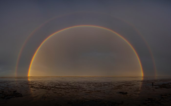 Double rainbow over a beach at low tide