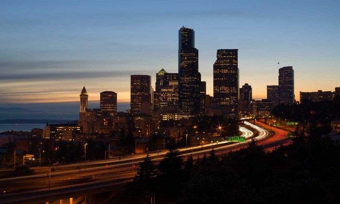 Seattle skyline at dusk with city lights and highway traffic