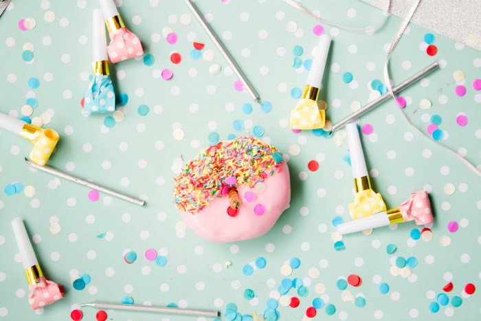 Pink frosted donut with sprinkles and party blowers