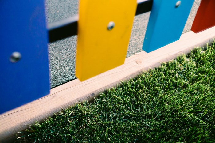Colorful fence with grass and playground surface