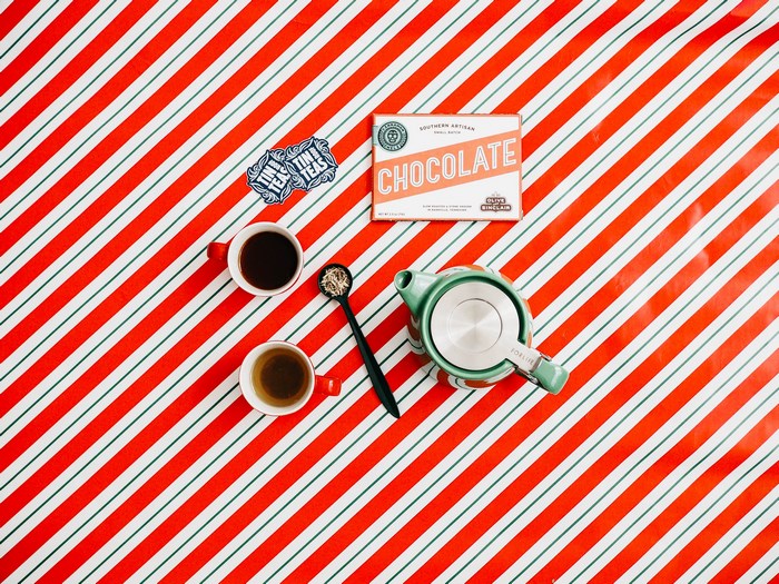 Chocolate bar, cups of tea, and teapot on striped tablecloth