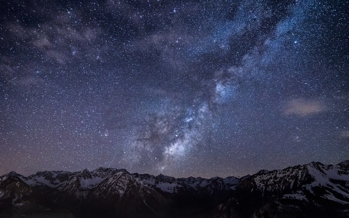 Milky Way over snow-capped mountains at night