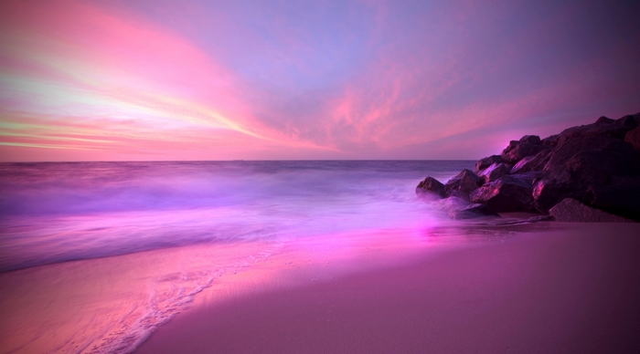 Pink and purple sunset over a beach with rocks
