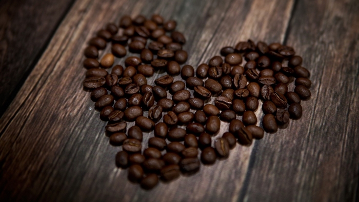 Heart shape made of coffee beans on wooden background