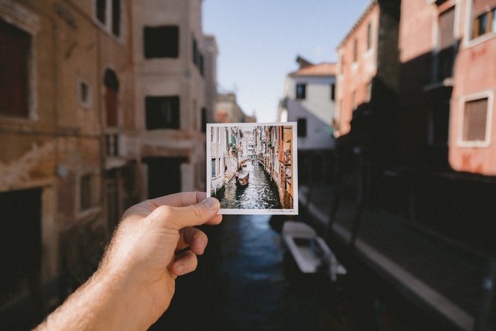 Hand holding postcard of Venice canal with gondola