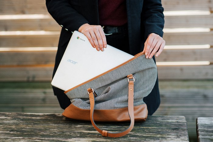 Woman packing Acer Chromebook into striped bag