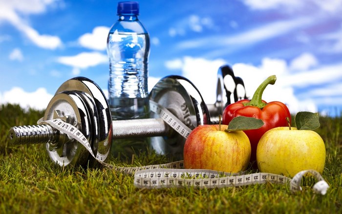 Dumbbells, apples, pepper, and water bottle on grass