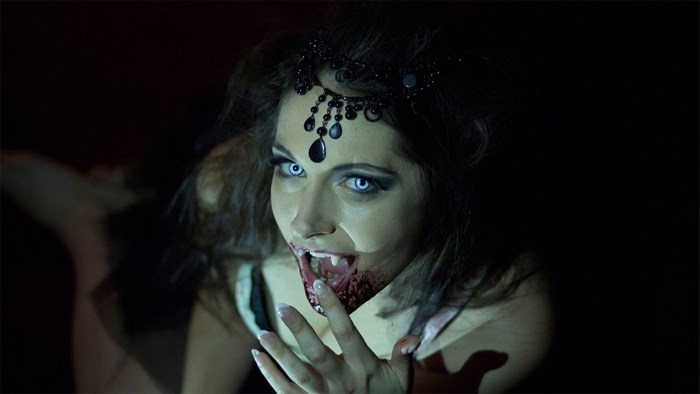 Vampire woman with white eyes and fangs