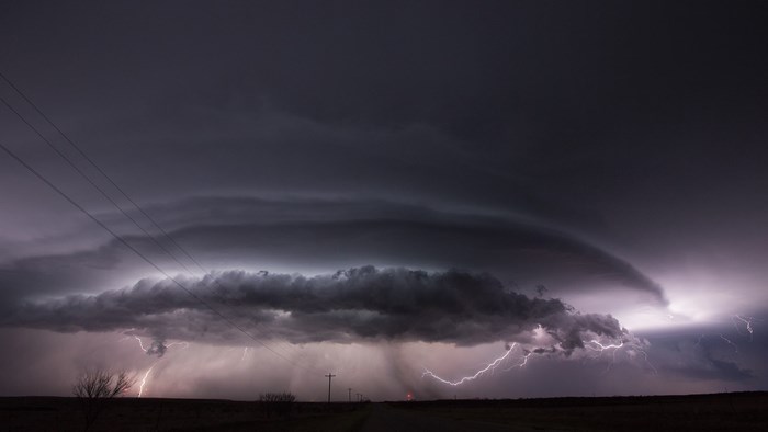Lightning strikes during a severe thunderstorm over a rural landscape