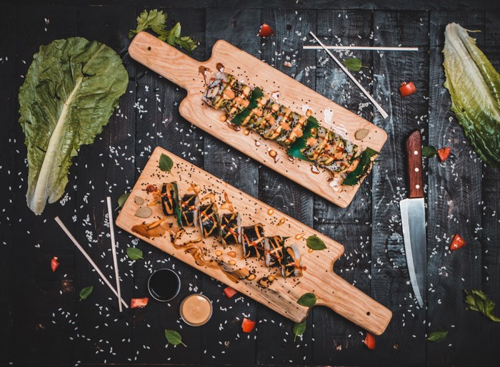 Sushi rolls on wooden serving boards with dipping sauces