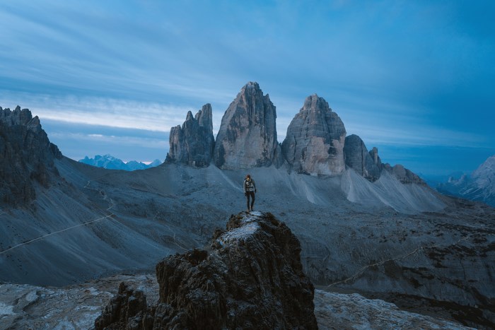 Person standing on a rock with Tre Cime di Lavaredo mountains