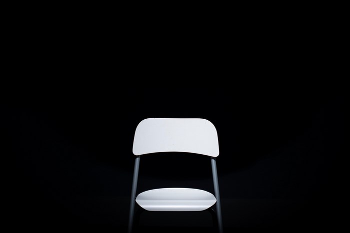 Minimalist white chair against a black background