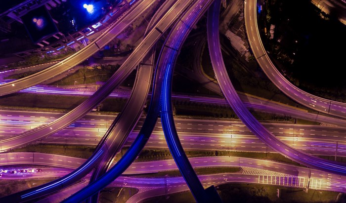Aerial view of a highway intersection at night with purple lights
