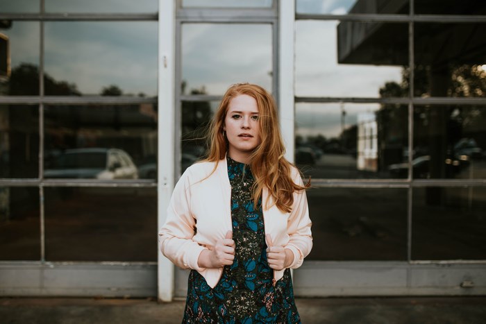 Woman with red hair in a light jacket and dress