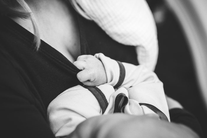 Baby's hand grabbing mother's shirt