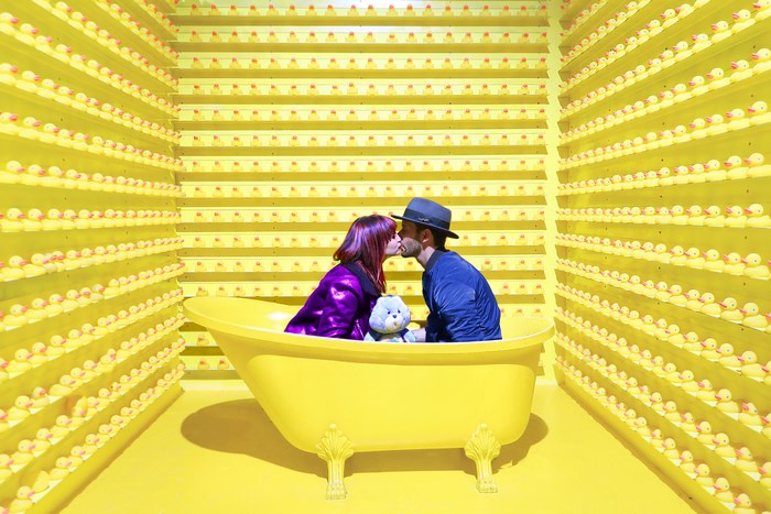 Couple kissing in a bathtub surrounded by rubber ducks