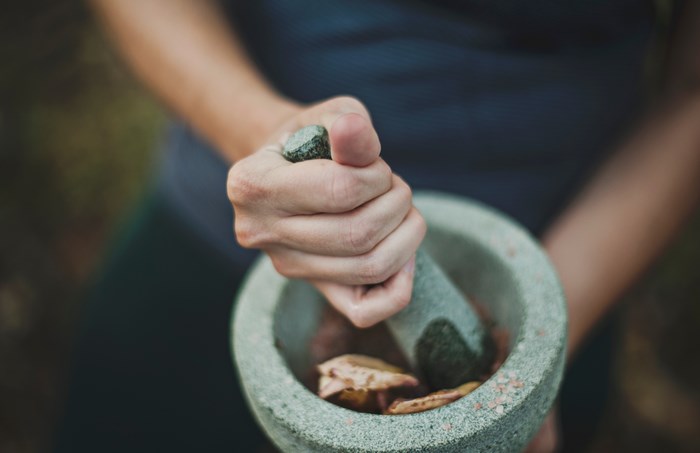 Person grinding ingredients in a mortar and pestle
