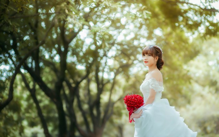 Bride in white dress holding red roses