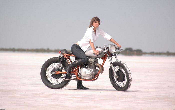 Girl on a custom cafe racer motorcycle on a salt flat