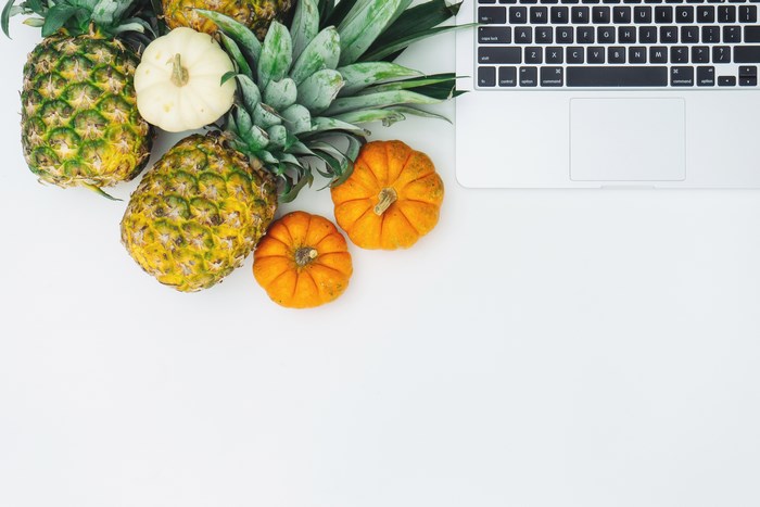Pineapples and pumpkins next to a laptop