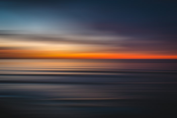 Blurry ocean sunset with orange and blue hues