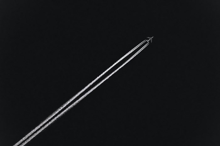 Airplane flying at night leaving jet trails