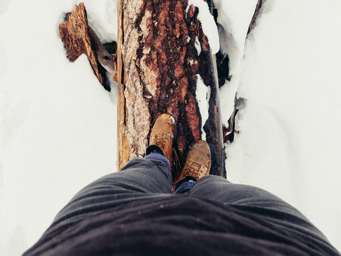 Person balancing on a log in the snow
