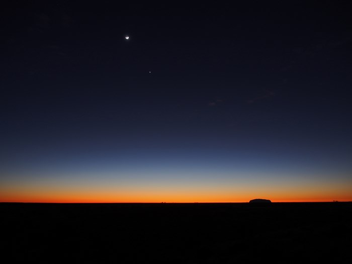 Moon and planet over Uluru at twilight