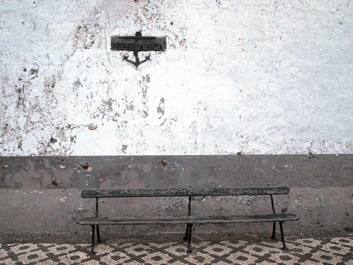 Old bench and 'Esperanca' sign with anchor on a textured wall