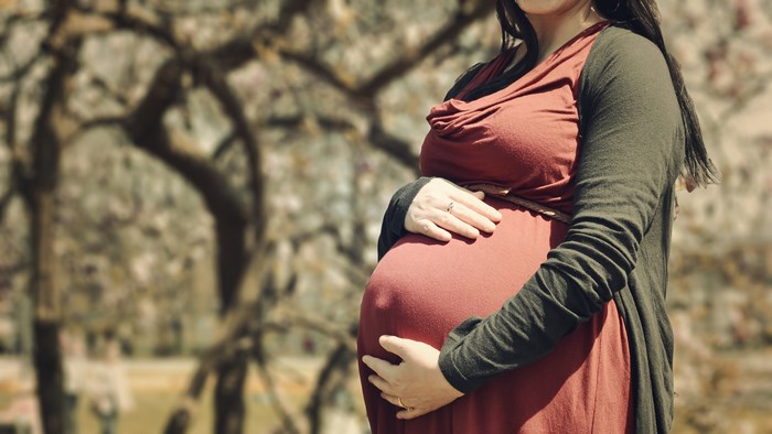 Pregnant woman holding her baby bump outdoors