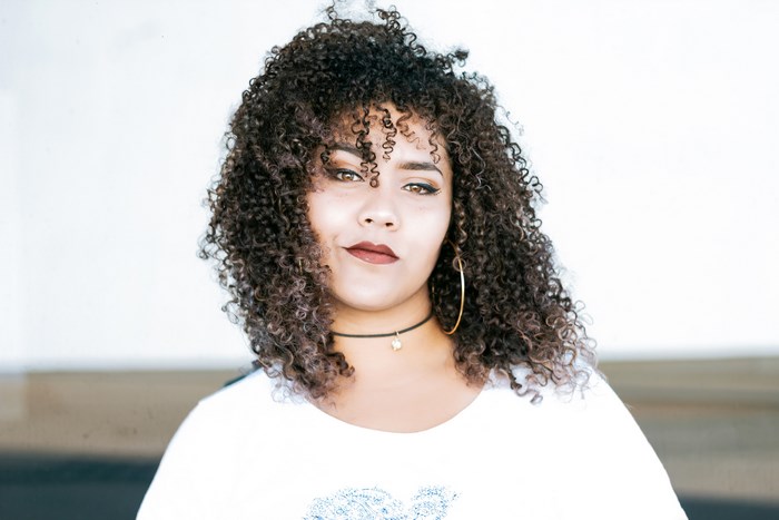 Woman with curly hair wearing a white shirt