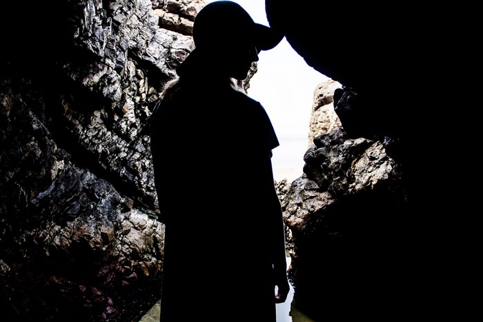 Silhouette of a person in a cave by the beach