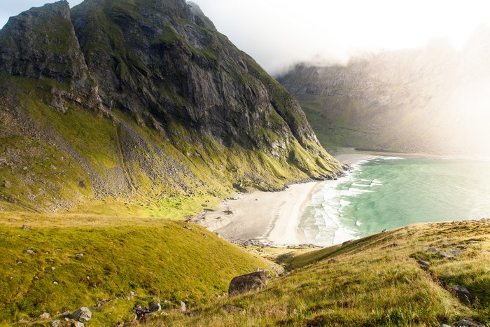Green mountains meet a sandy beach and turquoise ocean