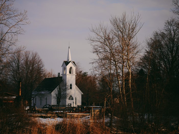 White Country Church with Steeple in Winter Woodland