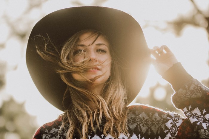 Woman in a wide-brimmed hat and sweater at sunset