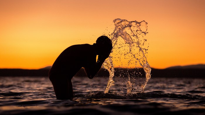 Man splashing water at sunset over the sea