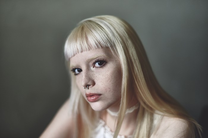 Portrait of a blonde woman with freckles and nose piercing