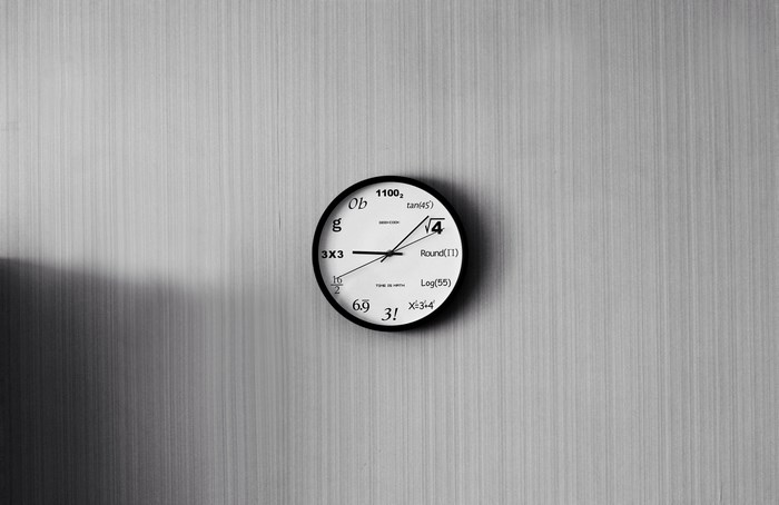 A math-themed clock on a textured wall