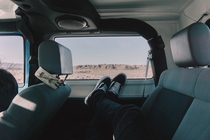 Man's feet resting in a car with desert landscape view