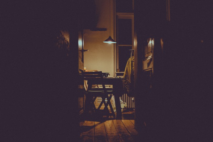 Cozy kitchen interior with a table, chairs, and a lamp at night