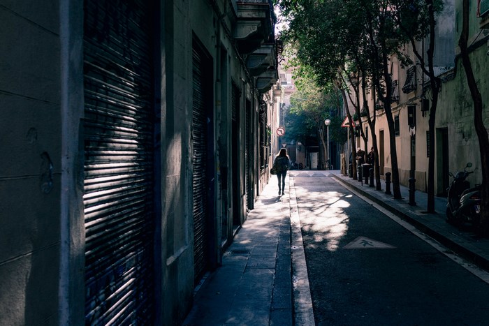 Woman walks down a sunlit street in a European town