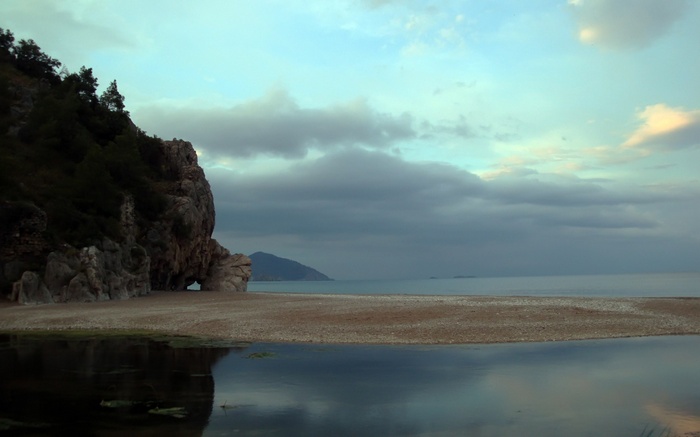 Rocky coastline with a calm sea and cloudy sky