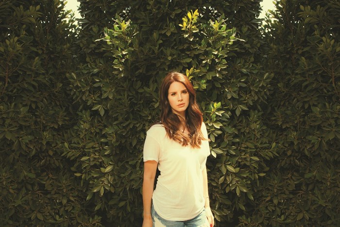 Lana Del Rey in front of green foliage