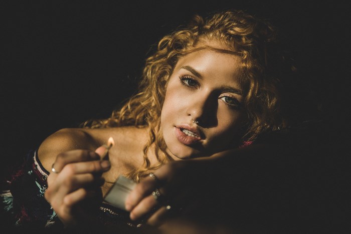 Woman holding a lit match in the dark