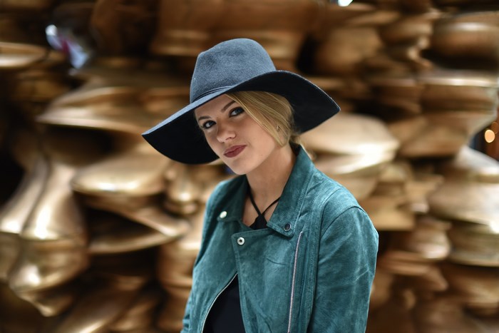 Woman in a wide-brimmed hat and teal jacket