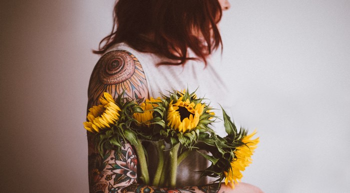 Tattooed woman holding a bouquet of sunflowers