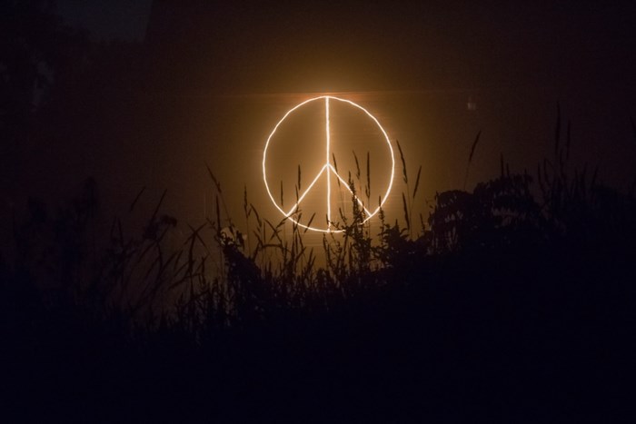 Peace sign illuminated at night with grass in foreground