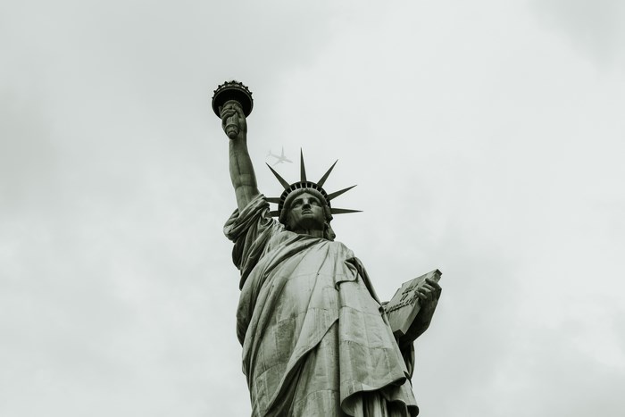 Statue of Liberty with an airplane in the sky